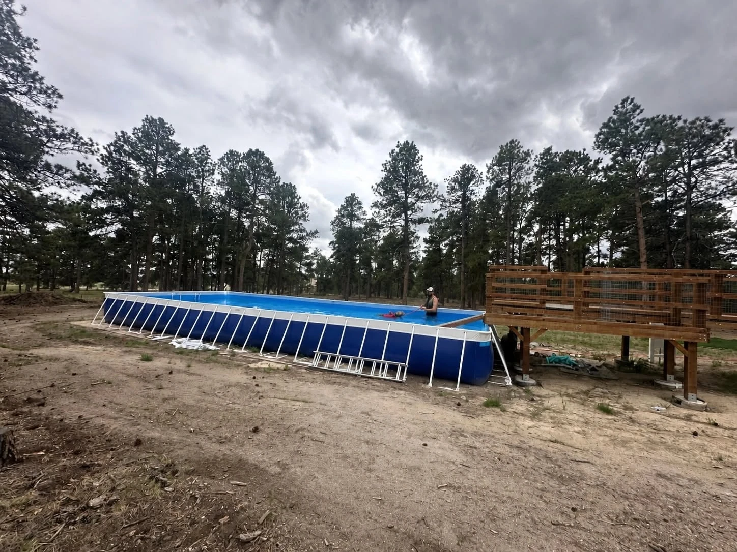 Outdoor pool and fenced activity area beneath Colorado skies